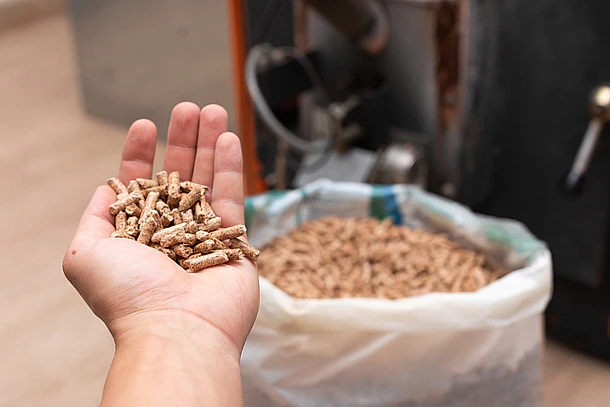 Sack voll Heizpellets aus der eine Hand einige herausgreift
